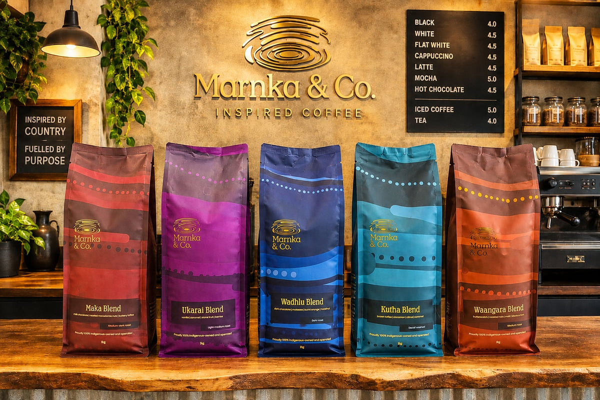 The five Marnka & Co. blends in their bags on a cafe counter beneath the gold Marnka & Co. logo